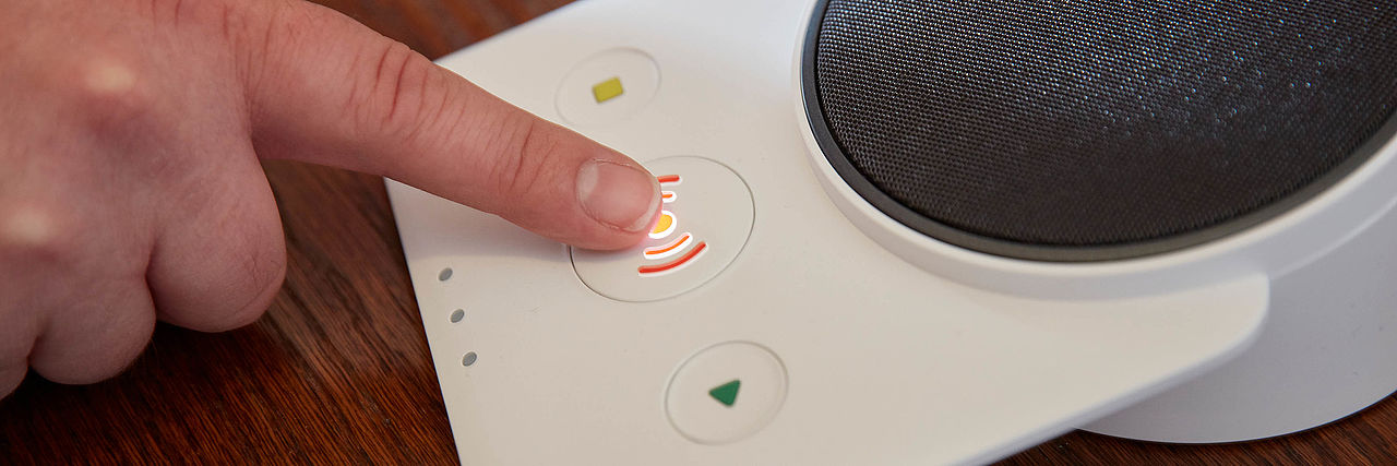 Unser DRK Hausnotruf Finger schwebt über der Alarmtaste des Hausnotrufgerät