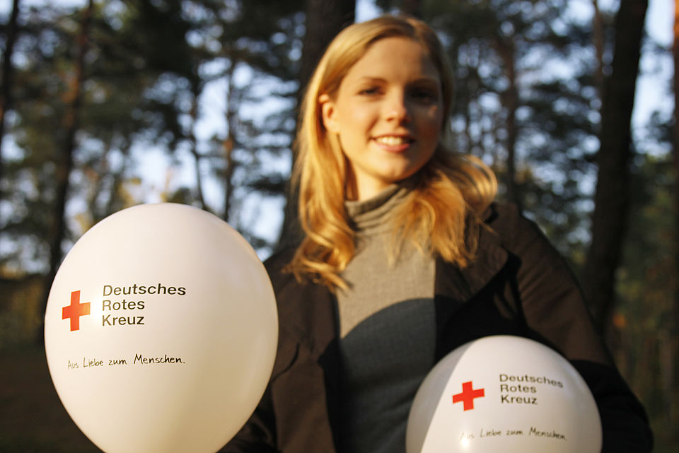 Einfach einmal reinschnuppern Junge Frau mit zwei DRK-Luftballons