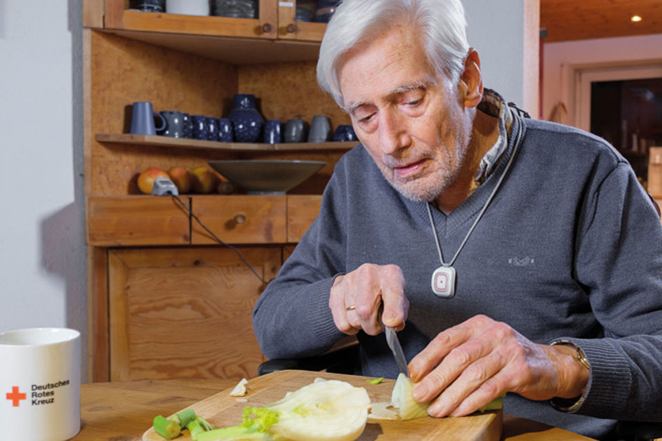 Hausnotruf für Senioren im Alltag älterer Mann schneidet Gemüse